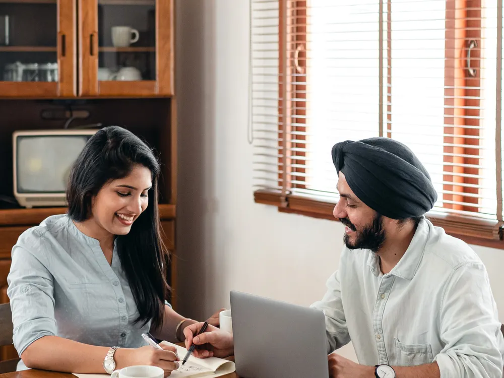 Two young professionals working through notes at a laptop
