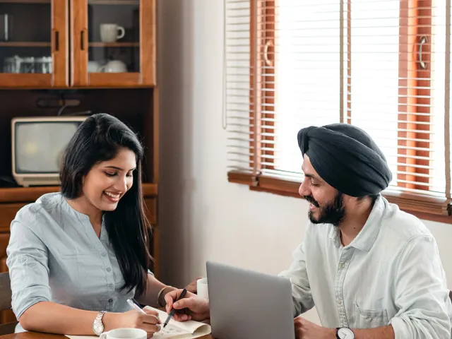 Two young professionals working through notes at a laptop