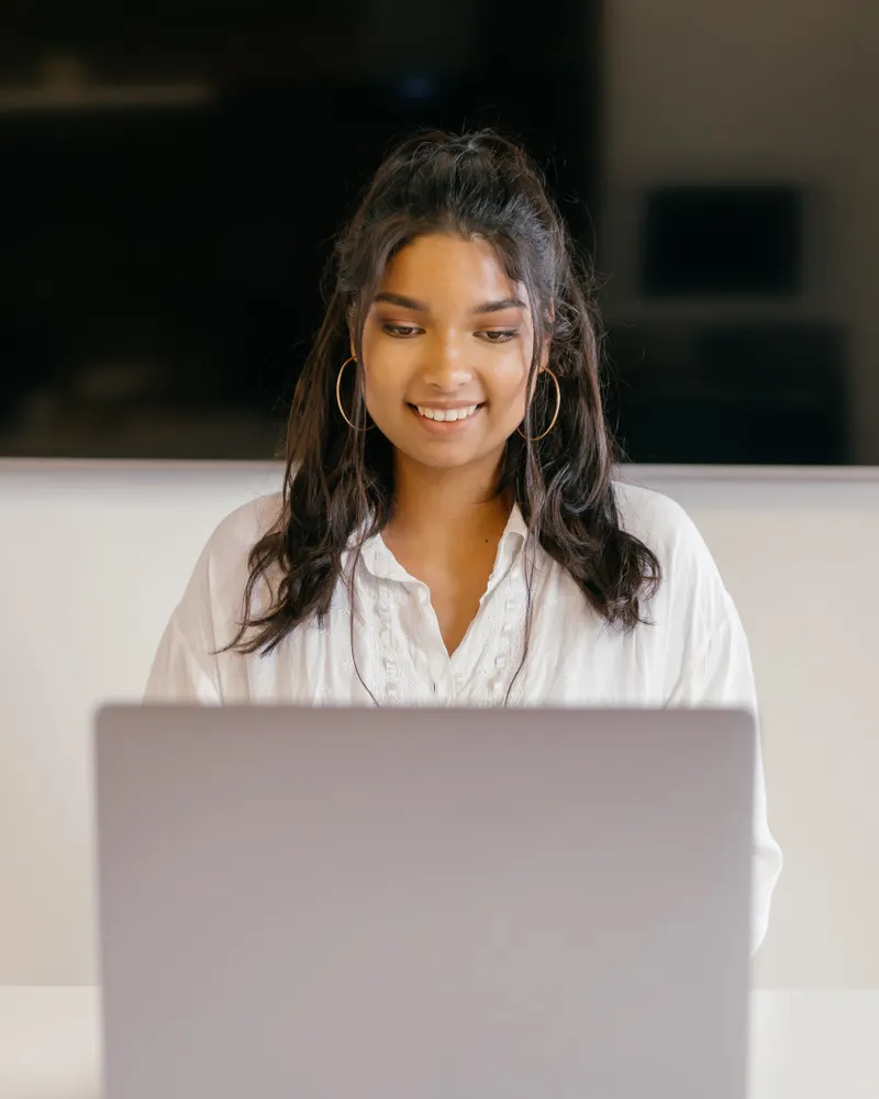A young woman smiling at her laptop