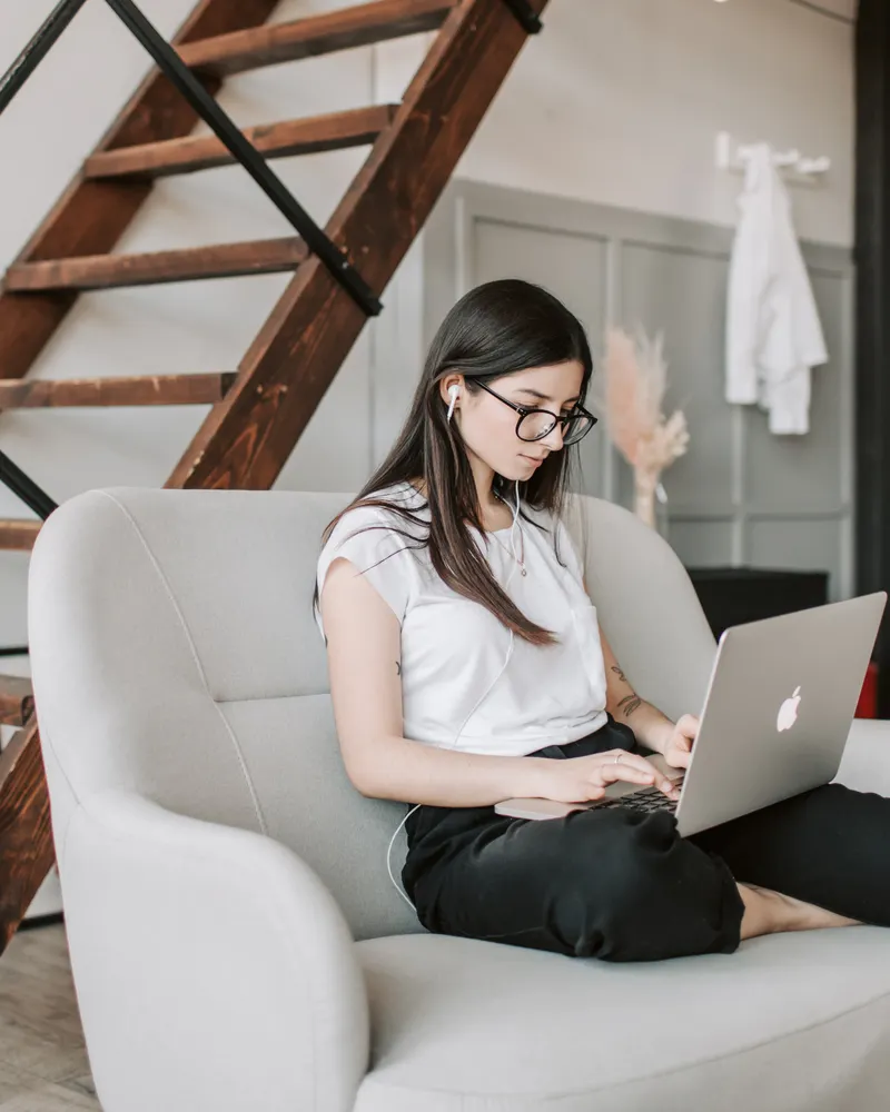 A person in glasses working on a laptop on a sofa